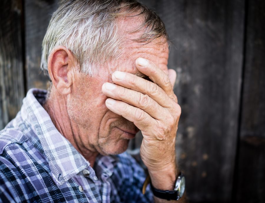 Desperate senior man suffering and covering face with hands in deep depression pain emotional disorder grief and desperation concept