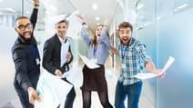 Group of joyful excited business people throwing papers and having fun in office