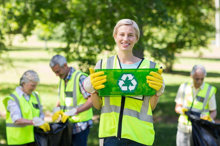 Happy mother holding recycling case on a sunny day