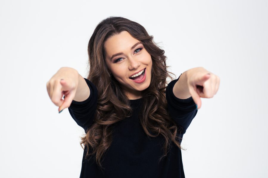 Portrait of a cheerful woman pointing at camera isolated on a white background 1