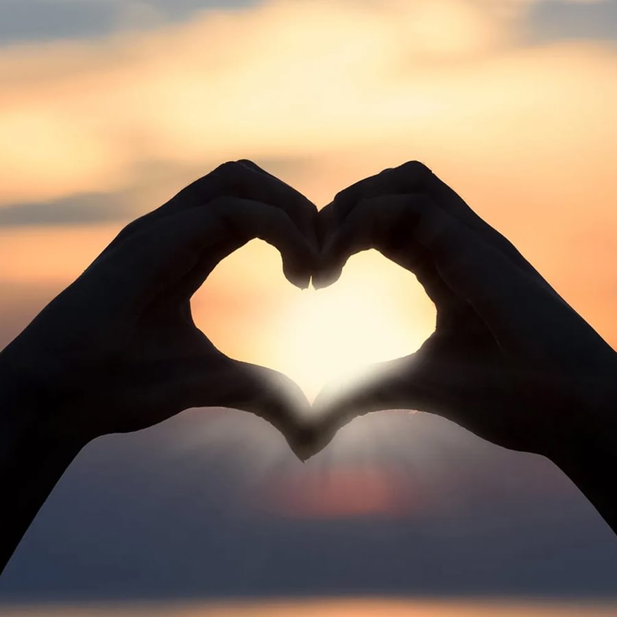Two hands making a heart shape in the sun.
