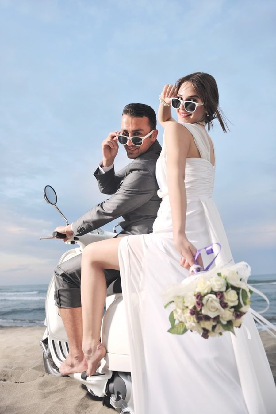 Wedding sce of bride and groom just married couple on the beach ride white scooter and have fun