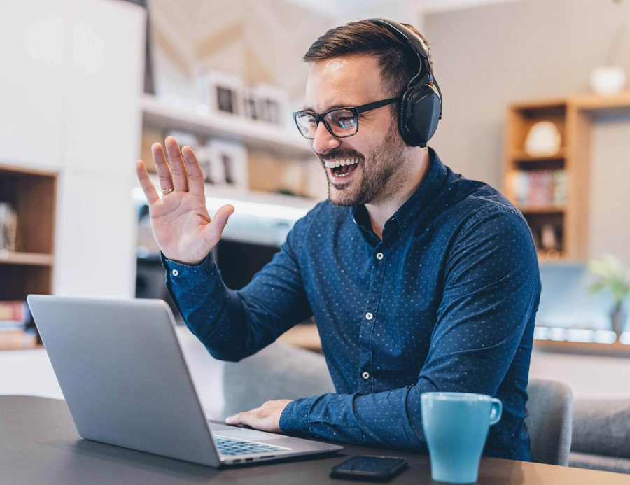 A man waving to his computer while on video chat.