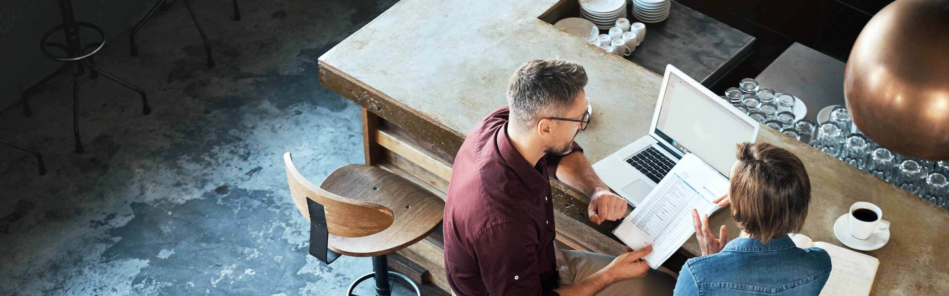 Looking down on a man and a women in an office, looking at a computer.