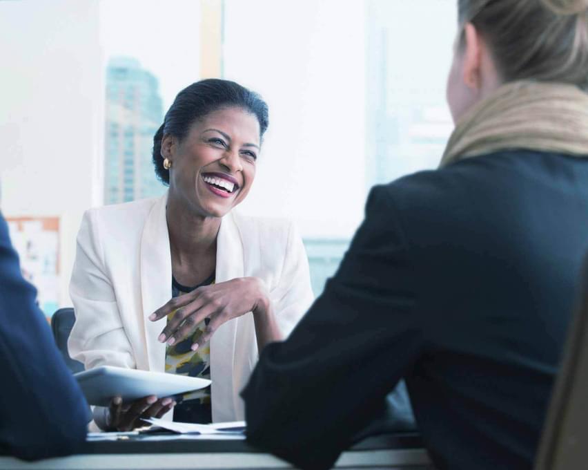 A women smiling in an office, meeting with a client.